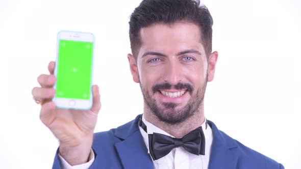 Face of Happy Young Bearded Businessman Showing Phone alt