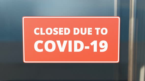 Closed due to COVID-19. Zooming in red close sign on the glass front door. 4K HD alt