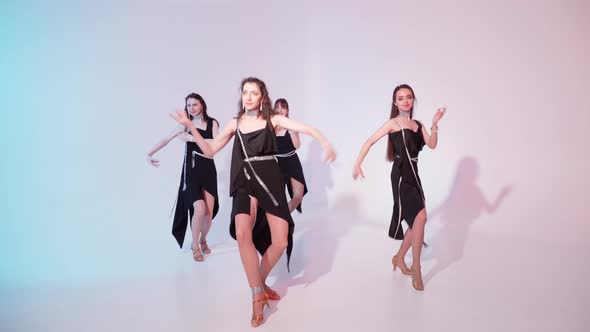 A Group of Four Girls in Elegant Black Dresses are Dancing in the Studio alt