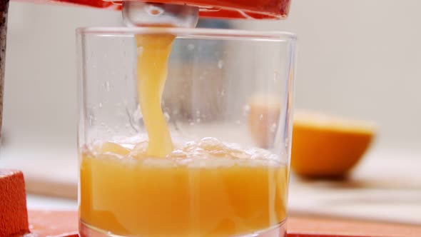 Super slow motion of fresh orange juice squeezed using a manual squeezer alt