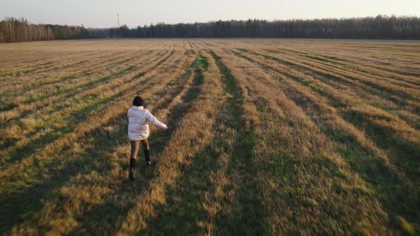 Teenage Girl Running Across the Field in the Evening alt