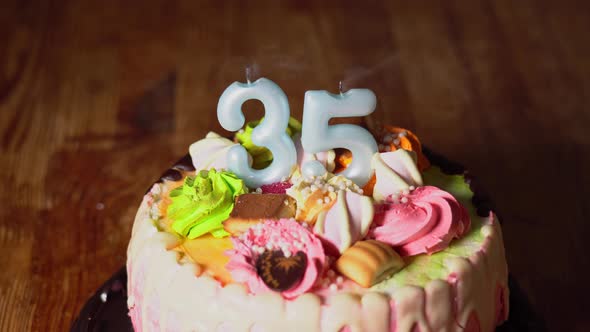 Blowing out candles on a birthday cake. 35th birthday. Birth cake with a burning birth candle alt