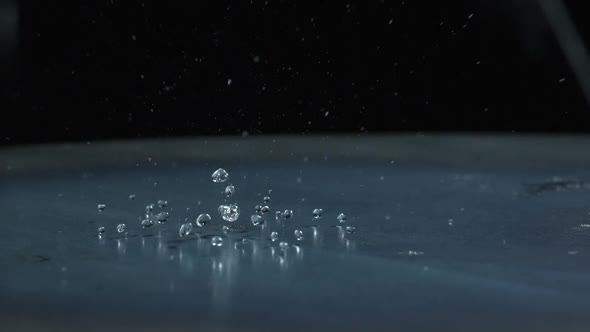 Slow motion of water droplets falling on metal surface. alt