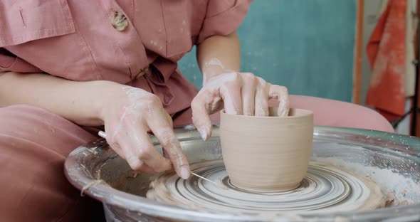 Female Potter Sitting and Makes a Cup on the Pottery Wheel. Woman Making Ceramic Item. Pottery alt