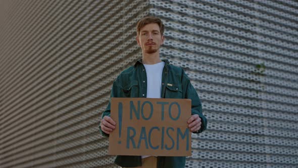 Man Holding Banner with Phrase No to Racism on Street alt