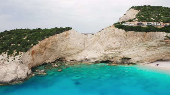 Drone shot of coastline with tall cliff and turquoise sea water. alt