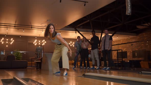 A Woman in a Bowling Alley Throws a Ball on the Track and Knocks Out a Shot in Slow Motion and Jumps alt