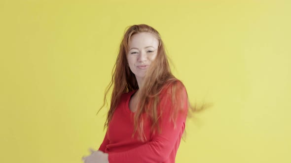 cheerful woman dancing energetically on isolated yellow background of studio