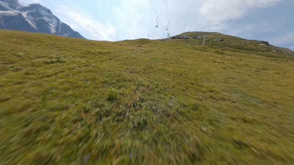 FPV Drone Extreme Flight Over Cable Road Hilly Terrain Covered Green Grass Lawn Ski Resort at Summer alt
