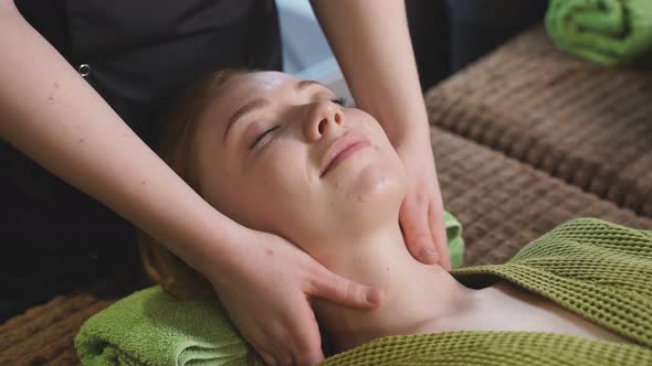 Calm Female Lie on Bed in Spa Salon Getting Massage on Neck and Chest