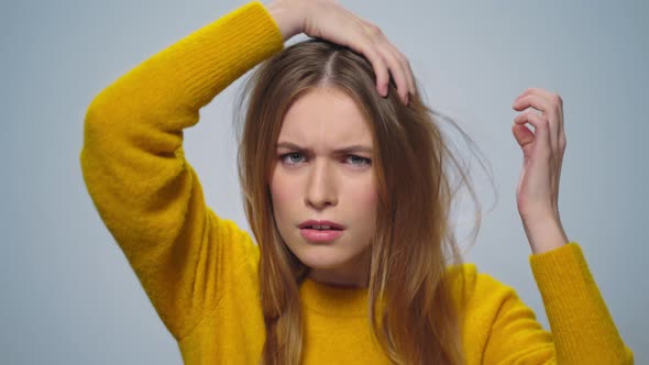 Portrait of Focused Attractive Woman Improving Appearance on Grey Background alt