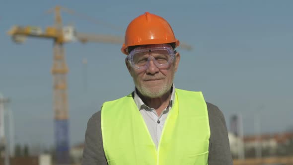 Portrait of an Elderly Engineer in Protective Clothing at a Construction Site alt