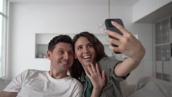 Young Man Grimaces and Smiles with Curly Wife Taking Selfies alt