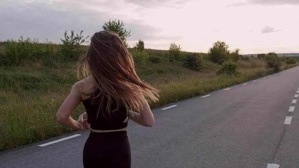 Rear View of Sporty Girl with Long Hair Jogging on Road at Beautiful Nature alt