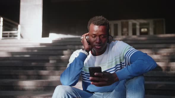 Black Young Man Listens to Music with Headphones