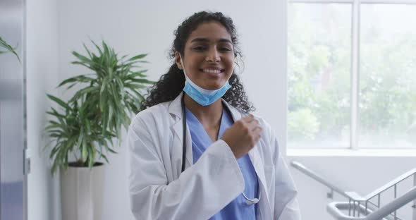 Portrait of asian female doctor lowering face mask and smiling in hospital alt