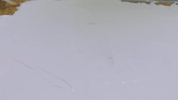 Large scale cake tray with icing being spread evenly across the surface. Pattern lined The tray is t alt