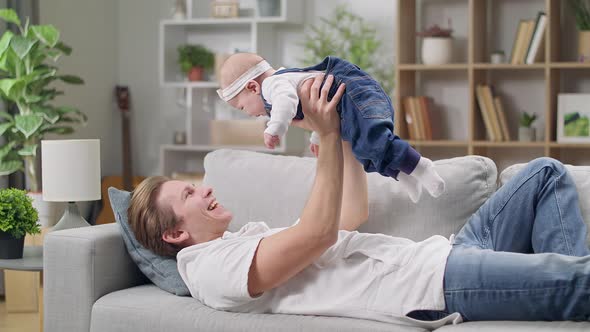 Dad Raises His Little Daughter Lying on the Couch Not alt