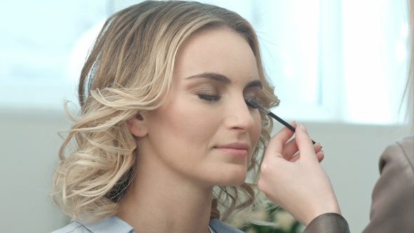 Professional Make-Up Artist Combing Eyelashes of Model