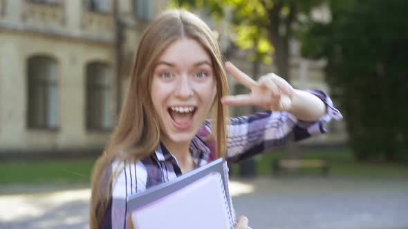 Student Girl Standing Near the University. Having Fun, Joking, Smiling, Showing Peace Sign