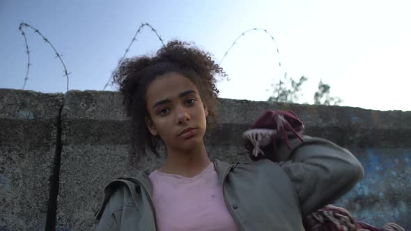 Biracial Teenage Girl Holding Bag, Dreaming to Escape From Refugee Camp, Poverty alt