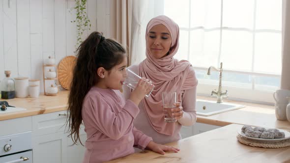 Cheerful Islamic Mom And Little Daughter Drinking Water At Home alt