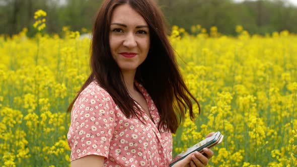 A beautiful cheerful young girl takes pictures of herself on the phone in a field alt