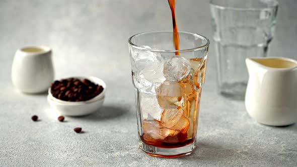 Pouring Cold Brewed Coffee over Ice. Making ice latte. Cold brew with ice and milk.