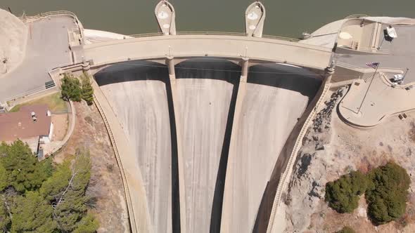 Drone flies back tilting up to reveal large San Gabriel Dam