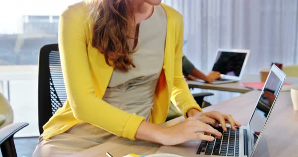 Businesswoman working on laptop at desk alt