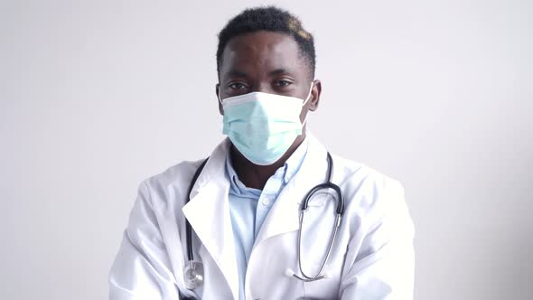 African Black Male Doctor Wears Face Mask Looking at Camera with Arms Crossed alt