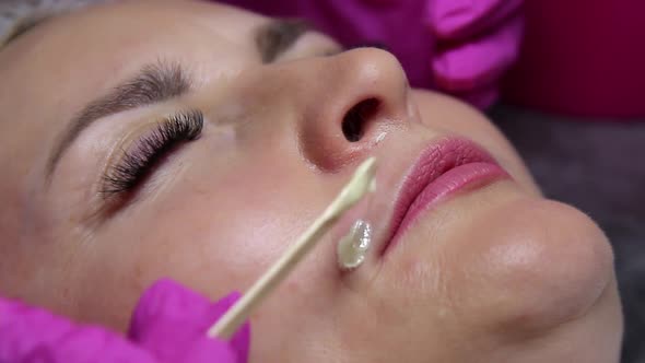 Beautician applies melted wax to the upper lip of the model to remove hair