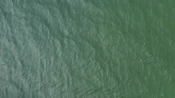 AERIAL: Lifting Up Above Green Sea With Waves Rippling All Over the Surface alt