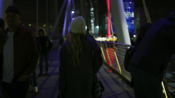 Woman Walking on The Golden Jubilee Bridge, at Night alt