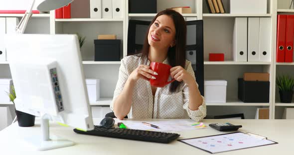 Businesswoman with Cup Smiling at Camera in Office