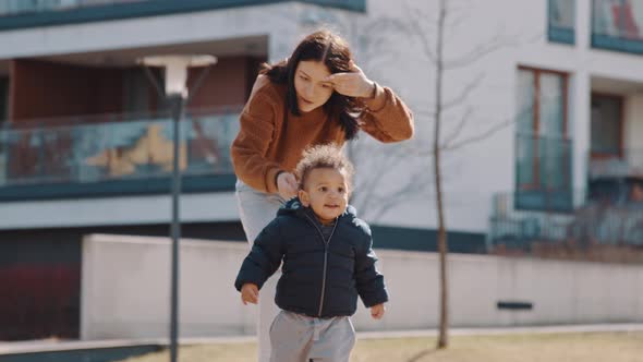 Happy and Excited Africanamerican Little Curled Boy Running From His Mother in the Park Medium Full alt