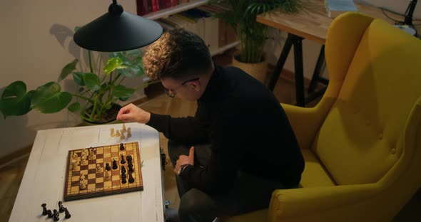 Man Plays Chess with Himself at Home at Night During Quarantine at Lockdown