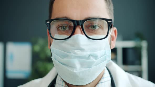 Close-up Portrait of Doctor Young Man in Glasses Wearing Mask Indoors in Hospital alt