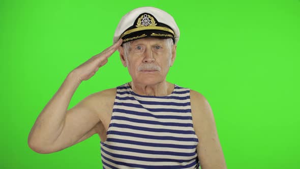 Elderly Sailor Man Salutes with Hand To Camera. Old Sailorman on Chroma Key alt