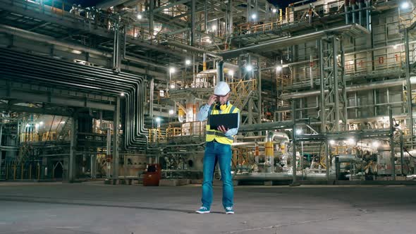 Male Expert is Using a Laptop on the Premises of the Refinery Plant alt