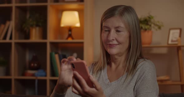 Crop View of Joyful Elederly Woman Touching Smartphone Screen While Sitting on Sofa at Home