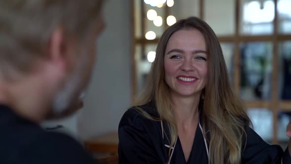 a Middle-aged Man and Woman Look at Each Other, Smile and Chat While Sitting at the Kitchen Table in alt
