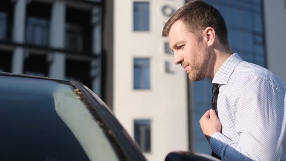 Businessman Puts on a Tie on the Street Looking Out the Window of His Car alt