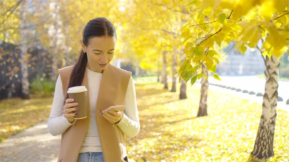 Fall Concept - Beautiful Woman Drinking Coffee in Autumn Park Under Fall Foliage