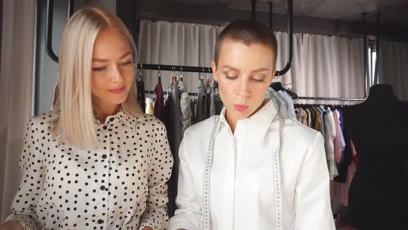 Caucasian Tailor Discuss Clothes Sketch with Interested Beautiful Client alt