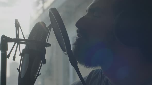 Closeup of the Attractive Bearded Man Singing Into a Microphone in Sun Backlight