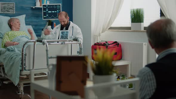 Doctor Holding x Ray Scan on Tablet for Retired Ill Patient alt