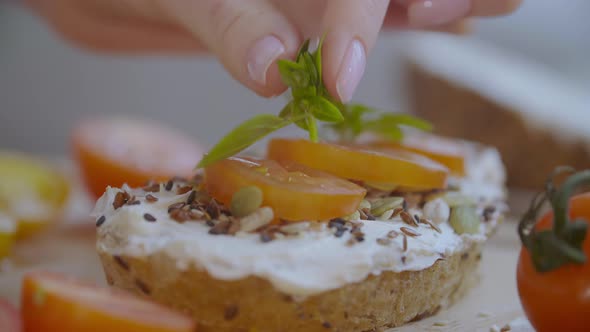 Woman Putting Herbs on Toast alt