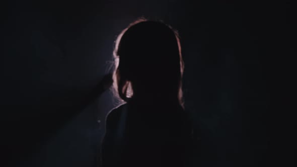 Close-up of the Face of the Singer with Microphone on a Black Smoky Background. The Singer Sings a alt