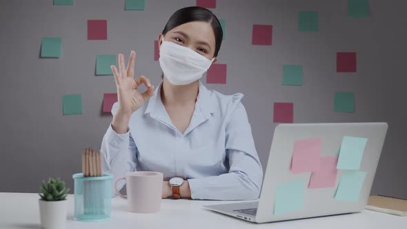 Asian woman wearing protective face mask happy and showing OK sign